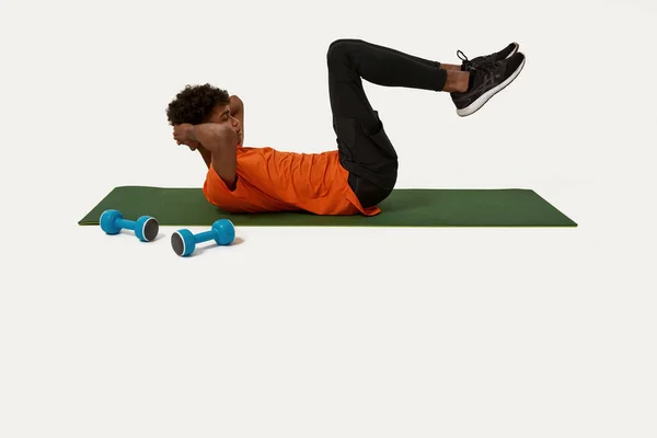 Side view of african man do abs on fitness mat — Stock Photo, Image