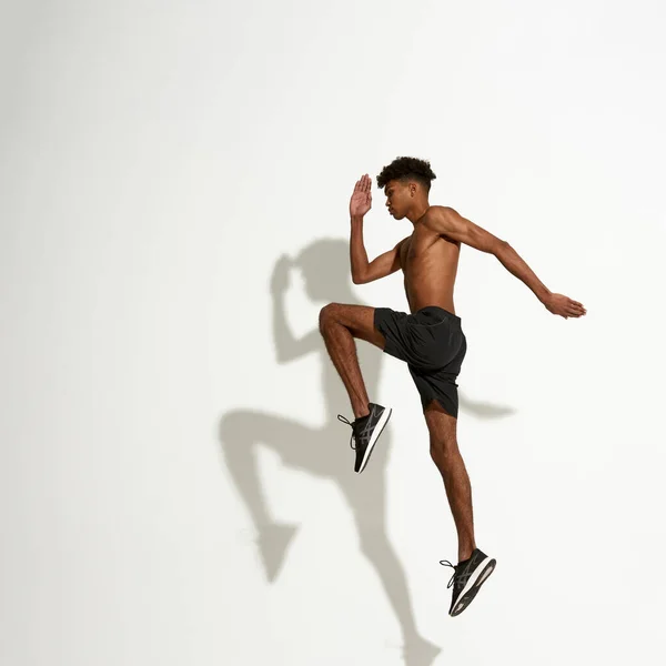 Vista lateral do jovem esportista africano pulando — Fotografia de Stock