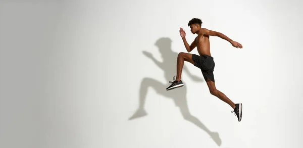 Vista lateral do atleta sério correndo e saltando — Fotografia de Stock