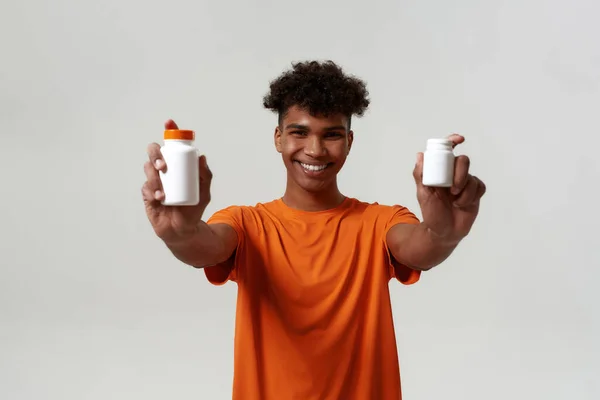 Black smiling man showing jars with medical pills — Stockfoto