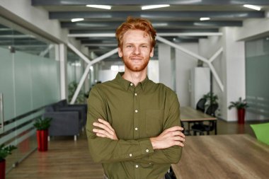 Çapraz kollu beyaz adam kameraya bakıyor.