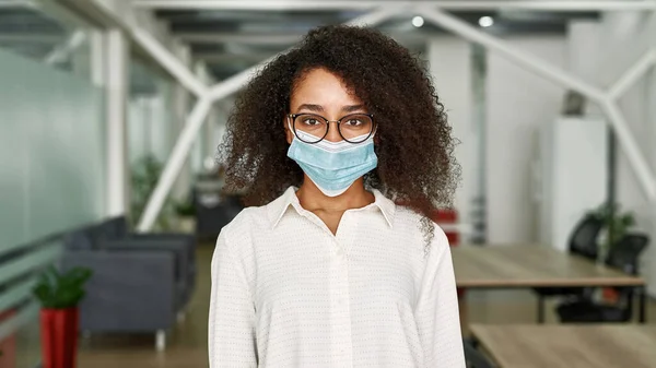 Joven mujer negra en máscara médica mira a la cámara —  Fotos de Stock