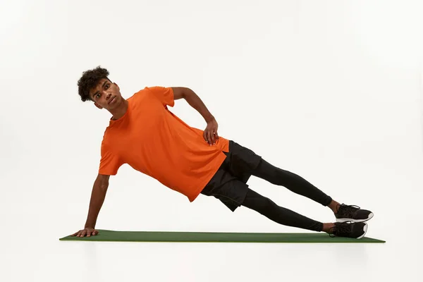 Černý sportovec dělá boční prkno na fitness podložce — Stock fotografie