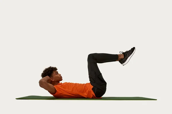 Boční pohled na kudrnatého sportovce dělat abs na fitness podložku — Stock fotografie