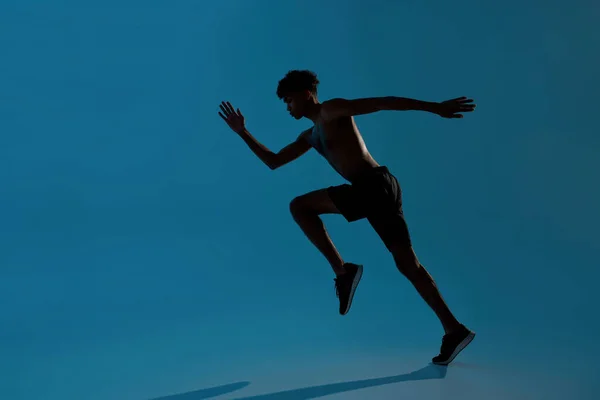 Homme sportif concentré courir sur fond bleu — Photo