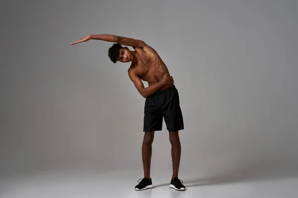 Esportista preto esticando e olhando para a câmera — Fotografia de Stock