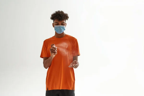 Černoch v lékařské masce aplikující dezinfekci — Stock fotografie