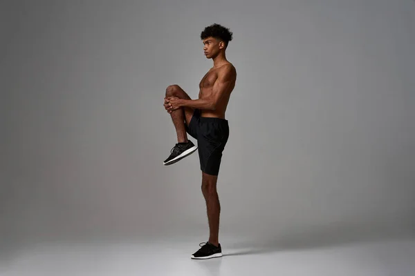 Side view of black serious sportsman stretch leg — Fotografia de Stock