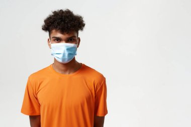 Tıbbi maskeli Afrikalı adam kameraya bakıyor.