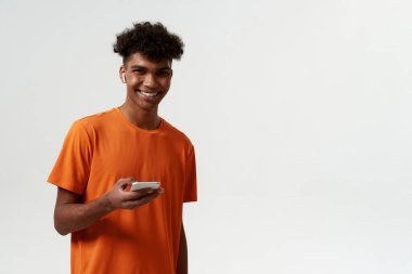 Akıllı telefonlu, kablosuz kulaklıklı siyah bir adam.