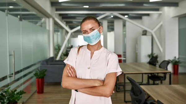 Mujer joven en máscara médica mirando a la cámara —  Fotos de Stock