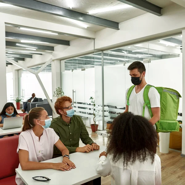 Courrier giving pizza and coffee to employees — Stock fotografie