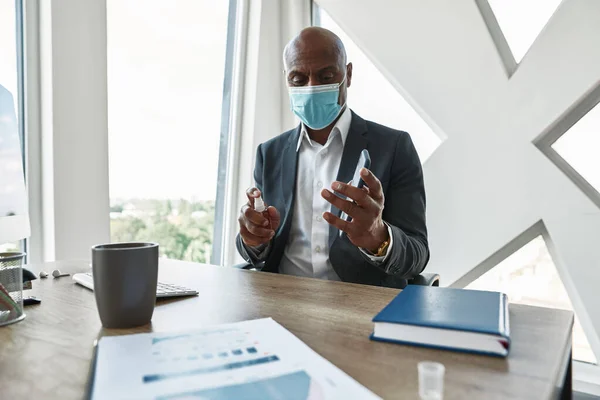 Black business man apply sanitizer on mobile phone — Stock fotografie