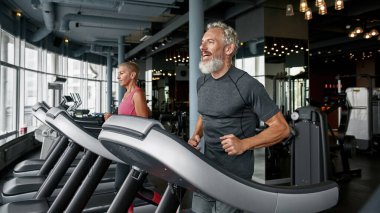 Cheerful couple exercising together on running track