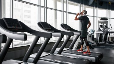 Elderly man stopped to dring while cardio training