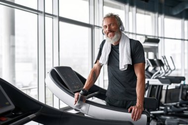 Tired but happy mature sportsman in gym