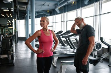 Attractive mature man and woman preparing for workout in gym