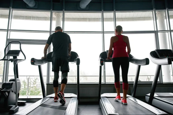Active lifestyle. Middle-aged couple walking on treadmills — Fotografia de Stock