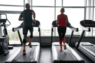 Senior people training on treadmills in gym