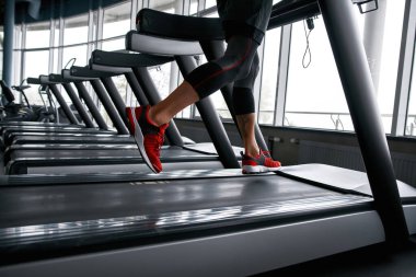 Male legs while jogging on treadmill, closeup
