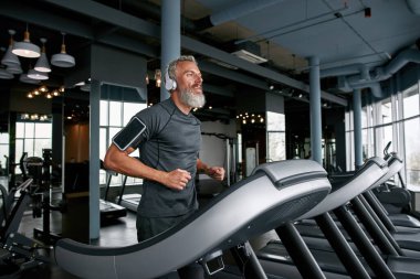 Tired mature man finishing running workout in gym
