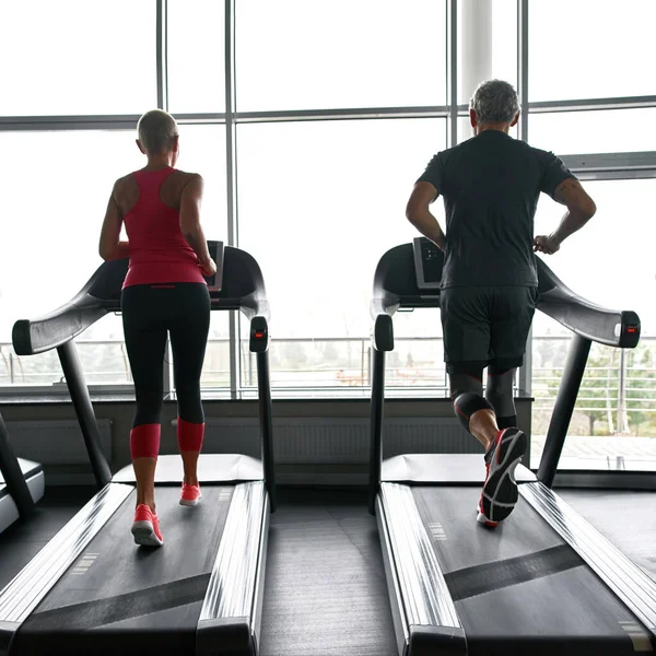 Active couple exercising on treadmills in sports center — Fotografia de Stock