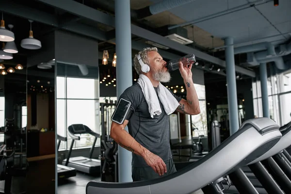 Hora de parar y beber agua mientras hace ejercicio en el gimnasio — Foto de Stock