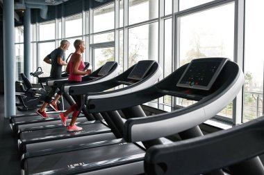 Senior couple running on treadmill in health club