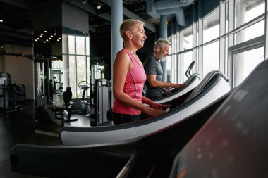 Side view of active seniors on stepping machine.