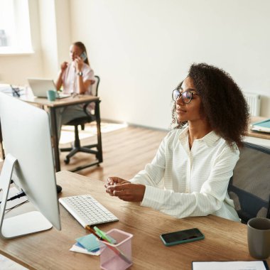 Black girl hold earphones while work in office