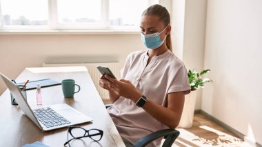 Young caucasian girl use smartphone while working
