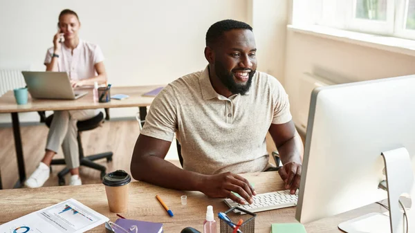 Black man watch on computer monitor while work — Stockfoto