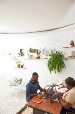 Çalışırken akıllı telefon kullanan bir adam kadına bakıyor.