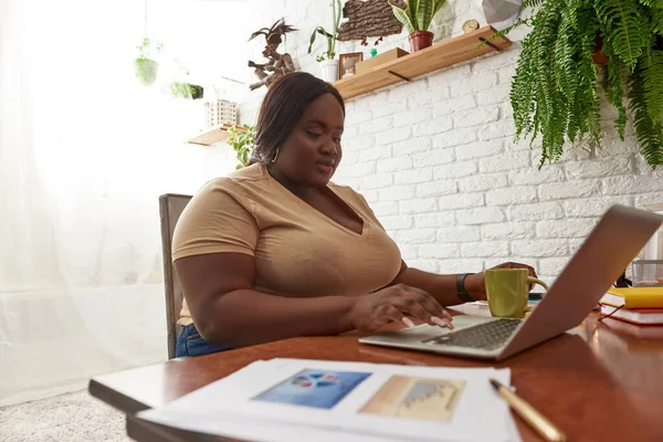 Fekete nő gépel és néz laptopon a munkahelyen — Stock Fotó