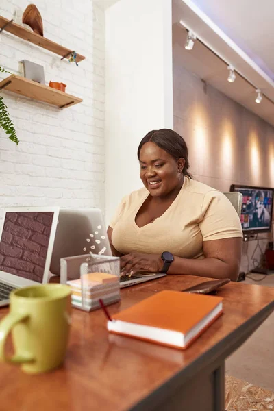 Siyah bir kadın dizüstü bilgisayarda yazıp izliyor.