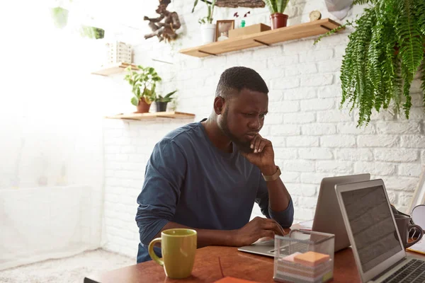 Átgondolt fekete férfi néz a laptopon a munkahelyen — Stock Fotó