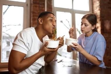 Çok ırklı çift video yarışmasında erişte yiyor.