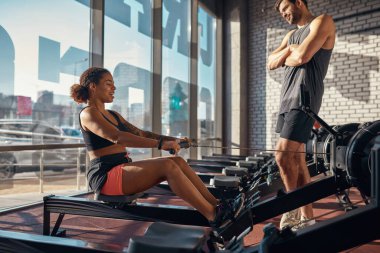 Antrenör sırt egzersizi yapan kıza bakıyor.