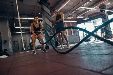 Eğitmenin alt tarafı, halatla kız egzersizine bak.