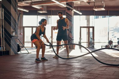 Antrenör söyler ve kız halatla egzersiz yapar.