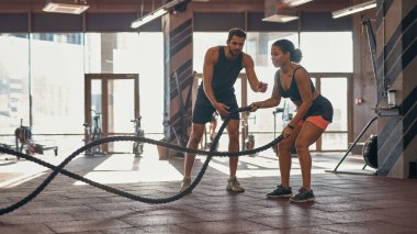 Antrenör siyah kıza spor ipiyle egzersiz yapmayı öğretiyor.