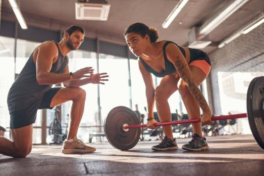 Eğitmenin dibi, kıza kaldırma hareketi yapıyor diyor.