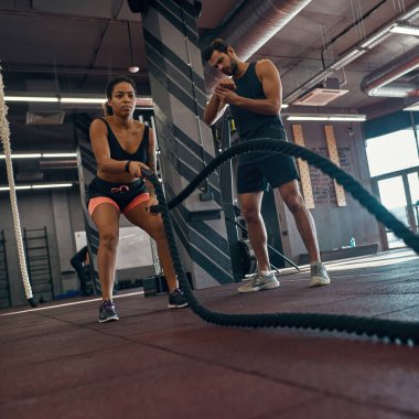 Antrenör kız egzersizi yaparken kol saatine bakıyor.