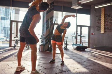 Siyah kız spor salonunda antrenörle ısınıyor.