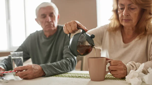 Mulher despeje chá quente de chaleira a xícara para o marido — Fotografia de Stock