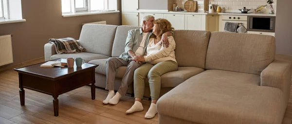 Couple d'âge mûr assis et reposant sur le canapé à la maison — Photo