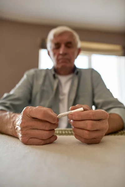 Concentre-se em mãos masculinas segurando cigarro na mesa — Fotografia de Stock