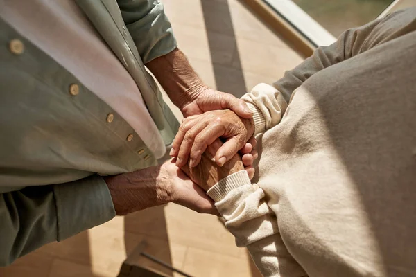 Обрезанные пожилой парой держатся за руки — стоковое фото