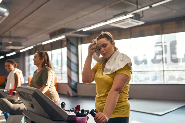 Tired girl run on treadmill and wipe forehead