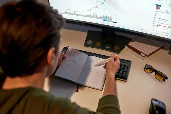 Male trader drawing business graph in notebook — Stock Photo, Image